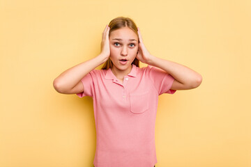 Young caucasian girl isolated on yellow background being shocked, she has remembered important...