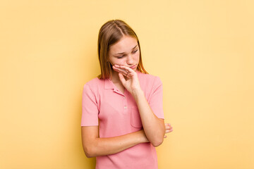 Young caucasian girl isolated on yellow background tired of a repetitive task.