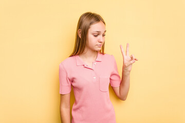 Young caucasian girl isolated on yellow background joyful and carefree showing a peace symbol with fingers.