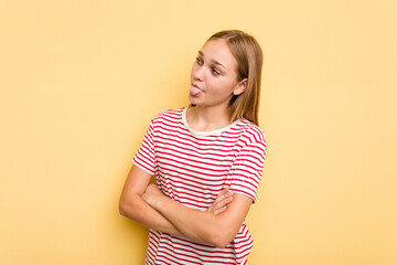 Obraz premium Young caucasian girl isolated on yellow background funny and friendly sticking out tongue.