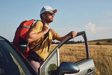 Naklejka premium Man camping and hiking in nature, unpacking from car outdoors, recreation and hobbies.