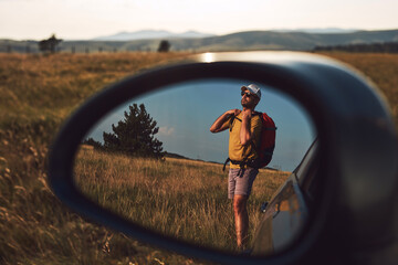 Man camping and hiking in nature, unpacking from car outdoors, recreation and hobbies.