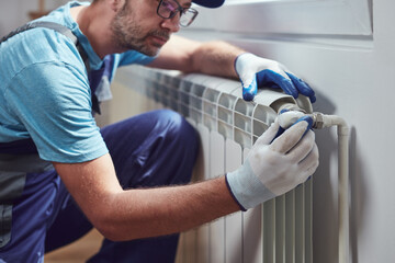 Obraz premium Central heating mechanic and handyman fixing home radiator, gas crisis and seasonal issues.