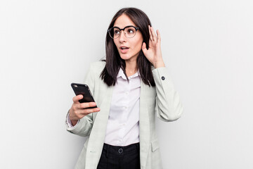 Young business caucasian woman holding mobile phone isolated on white background trying to listening a gossip.