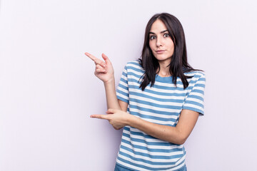 Young caucasian woman isolated on pink background shocked pointing with index fingers to a copy space.