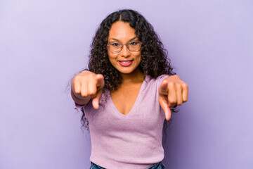 Young hispanic woman isolated on purple background cheerful smiles pointing to front.