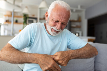 Elderly man has pain in fingers and hands. Old man with finger pain, Man massaging his arthritic hand and wrist. - obrazy, fototapety, plakaty