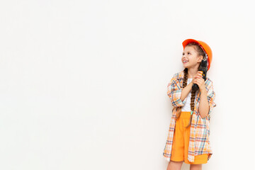 A child with a screwdriver and wearing a construction safety helmet on a white isolated background looks and shows your advertisement. The concept of renovation in the children's room.