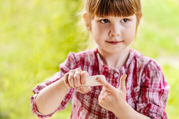 A little blurry girl washes her hands with soap on the street in the village. A pretty 4-year-old girl is holding a bar of soap in her hands. Protection against infections, viruses and bacteria.