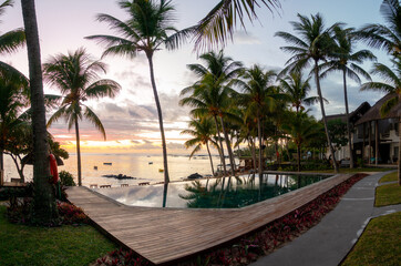 Fototapeta na wymiar Sunrise with reflection at at hotel pool in Belle Mare, Mauritius