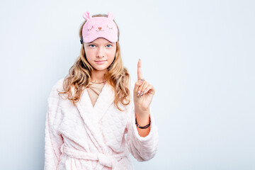 Caucasian teen girl wearing a pajama isolated on blue background showing number one with finger.