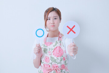 ✖️の札を突き出すエプロン姿の女性