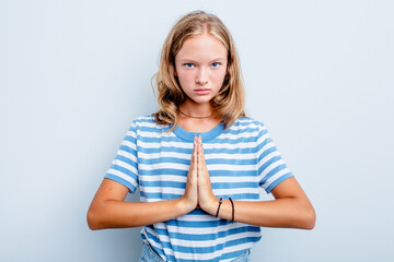 Caucasian teen girl isolated on blue background praying, showing devotion, religious person looking...