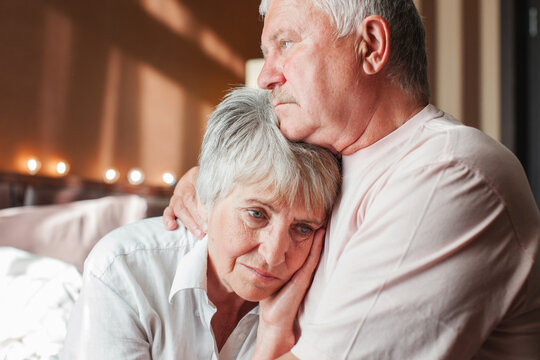 Worried senior woman embracing upset old man