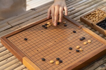 go player hand showing how to hold and place the piece on board. female hand places a go wooden on the board in a game of Go - Game go.