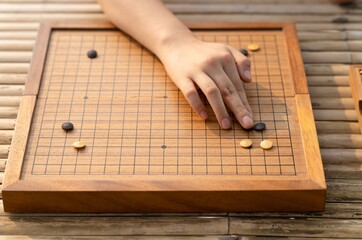 go player hand showing how to hold and place the piece on board. female hand places a go wooden on the board in a game of Go - Game go.