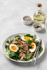 Tuna salad with boiled egg and spinach on white plate. Keto diet, healthy food. Fresh salad bowl. Dinner.