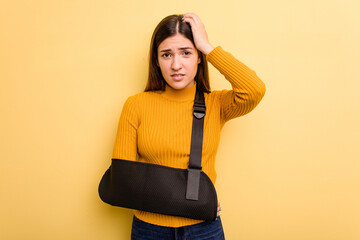 Young caucasian woman with broke arm isolated on yellow background being shocked, she has remembered important meeting.