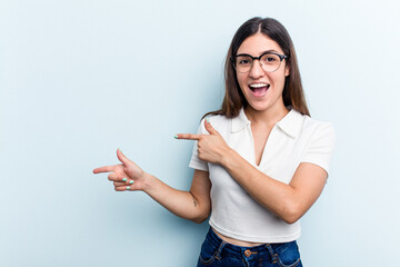 Young caucasian woman isolated on blue background excited pointing with forefingers away.