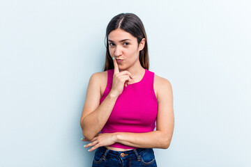 Young caucasian woman isolated on blue background contemplating, planning a strategy, thinking about the way of a business.