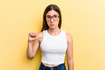 Young caucasian woman isolated on yellow background showing a dislike gesture, thumbs down....