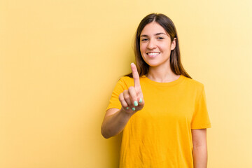 Young caucasian woman isolated on yellow background showing number one with finger.