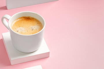 Cappuccino in coffee cup on square white podium and pink background. Espresso, ristretto drink on...
