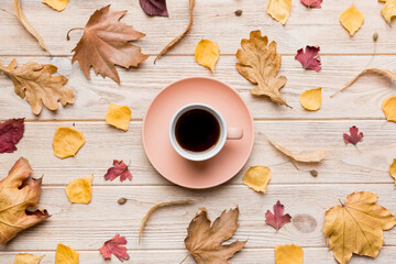 Flat lay composition with colorful Autumn cup of coffee and leaves on a color background. top view