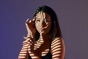Lines is on the skin. Beautiful young woman is in projector neon lights in the studio