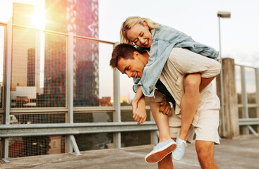 summer holidays, love and people concept - happy young couple having fun on roof top parking