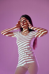 Purple colored background. Beautiful young woman is in projector neon lights in the studio