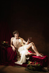 Fototapeta premium Artistic portrait of young handsome man in image of famous historical character, medieval person isolated on dark vintage background. Retro style