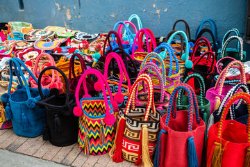 colorful straw handbags are displayed in market stall