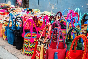 colorful straw handbags are displayed in market stall