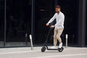 Stylish man is with his scooter outdoors at daytime