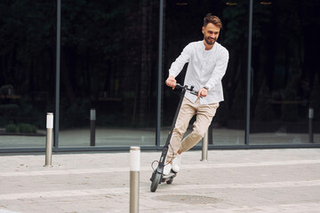 Stylish man is with his scooter outdoors at daytime