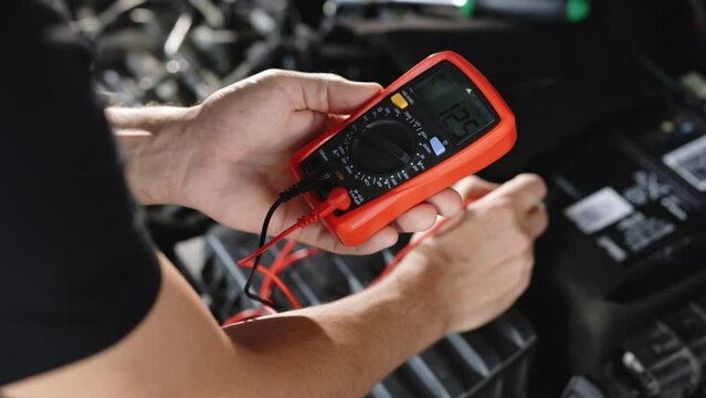 Man using multimeter to measure the voltage of the batteries. Mechanic doing car inspection, he is testing car battery with tester. Check battery voltage with electric multimeter