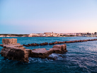 Rocky coast and beach in Otranto at sunset, Old town of Otranto in southern Italy in Puglia by the...