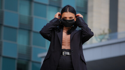 Young hispanic girl standing on city building background looking at camera businesswoman wearing medical protective mask protects health from viral infection during pandemic air pollution quarantine