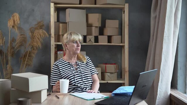 Time For Coffee Break. Older Woman Small Business Owner In Casual Wear Holding A Cup Of Coffee While Sitting At Her Working Place In Home Office. Start Up And SME