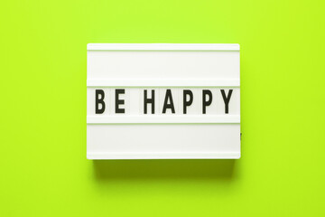 Lightbox with word be happy on green background, top view. Space for text