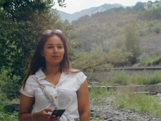 young latina indian woman relaxing in the river outdoors using smartphone