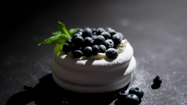 Mini meringue dessert pavlova cake with fresh blueberries plased on dark rusty table