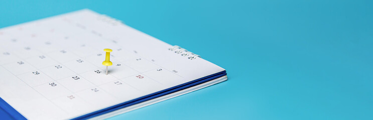 Yellow pin on event calendar. Planner calendar on blue background, plan for business meetings.

