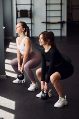 Lifting the weights. Two women in sportive clothes have fitness day in the gym together