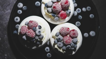 Delicious mini pavlova meringue desserts served with frozen frosty berries