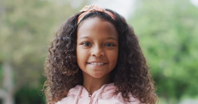 Video portrait of happy african american girl with long curly hair smiling to camera in garden