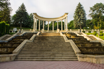 Park landscape - high steps of a cascade staircase and a rotunda with columns among the lush green foliage of trees and bushes in Kisolovodsk russia on a summer day