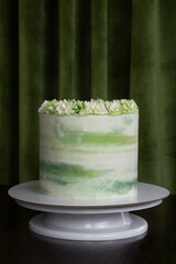 tall cake with green cream on juicy green background with a copy space