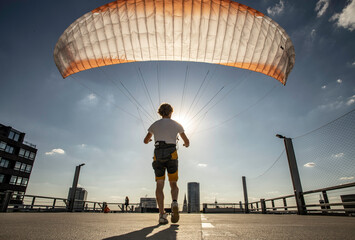 Man inflating paraglider in building top of Cologne city